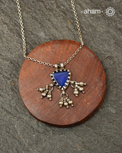 A charming piece inspired by traditional tribal adornments, this neckpiece features a vibrant blue glass pendant accented with silver ghungroos that sway gently with movement. The striking colour of the glass contrasts beautifully with the rustic silver finish, creating a look that is both distinctive and effortless.

Lightweight and easy to style, it pairs beautifully with handloom sarees, cotton kurtas, dresses, and everyday separates.