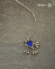 A charming piece inspired by traditional tribal adornments, this neckpiece features a vibrant blue glass pendant accented with silver ghungroos that sway gently with movement. The striking colour of the glass contrasts beautifully with the rustic silver finish, creating a look that is both distinctive and effortless.

Lightweight and easy to style, it pairs beautifully with handloom sarees, cotton kurtas, dresses, and everyday separates.