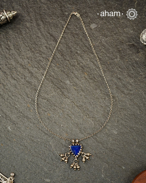 A charming piece inspired by traditional tribal adornments, this neckpiece features a vibrant blue glass pendant accented with silver ghungroos that sway gently with movement. The striking colour of the glass contrasts beautifully with the rustic silver finish, creating a look that is both distinctive and effortless.

Lightweight and easy to style, it pairs beautifully with handloom sarees, cotton kurtas, dresses, and everyday separates.