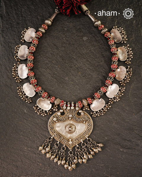 This vintage silver neckpiece features a central pendant shaped like a barbed arrowhead form. It is adorned with 12 silver flat textured plaques, all strung together on cotton thread. A big bold statement piece.