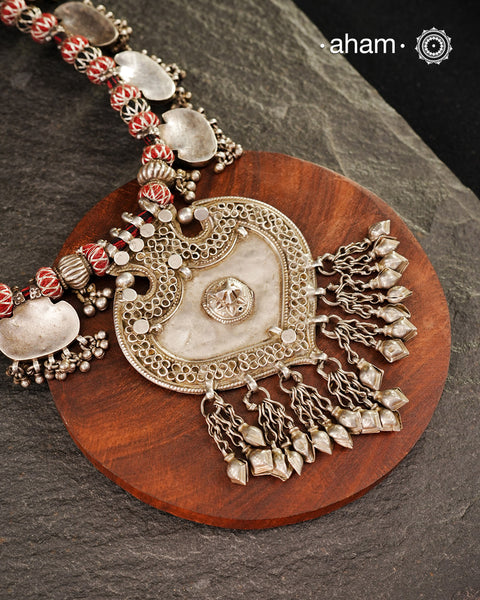 This vintage silver neckpiece features a central pendant shaped like a barbed arrowhead form. It is adorned with 12 silver flat textured plaques, all strung together on cotton thread. A big bold statement piece.