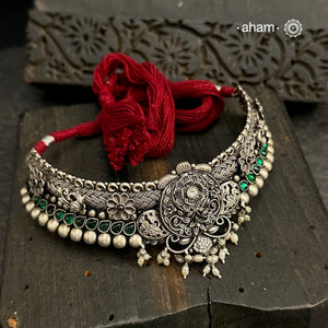 This Shivneri Silver Maharashtrian Thushi showcases the intricate craftsmanship of kolhapuri artisans Made from 92.5 silver, it features beautiful green stone highlights and elegant pearls for a stunning addition to any outfit. Expertly crafted, this necklace is perfect for those looking for a touch of traditional elegance.