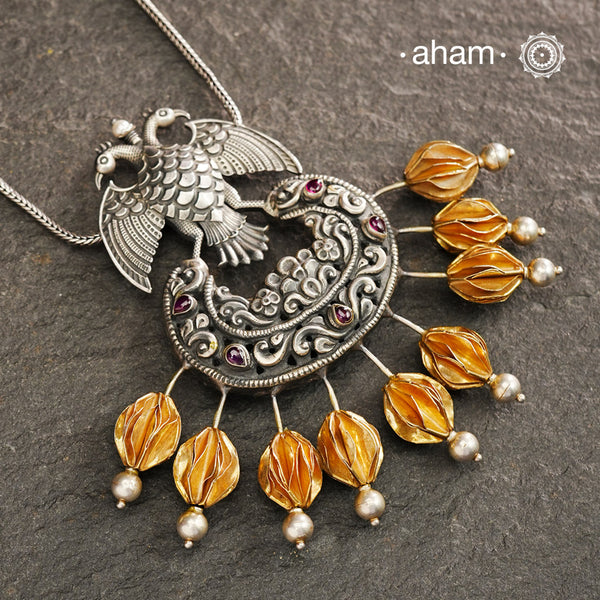 We thrive to bring alive traditional forms in new avatars. This Noori Dual tone Gandaberunda pendant is crafted in 92.5 sterling silver using traditional techniques, studded with maroon spinel drops and intricate nakshi work. Perfect for those who admire and cherish traditional jewellery. Please note the pendant does not come with a chain