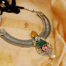 A beautiful contemporary dual tone neckpiece with the majestic Gir lion at the center, accompanied by craved green aventurine, beautiful peacock and lotus motifs, pink kundan highlight and finished off with a baroque pearl. Crafted in silver by karigars in India.&nbsp;