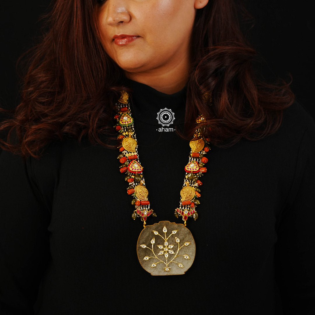 This stylish Noori Dual Tone Silver Neckpiece is perfect for any special occasion. It features a dual tone silver neckpiece with a large jade stone pendant and kundan inlay work. The piece is highlighted by coral and semi-precious beads, adding an elegant touch. Perfect for any occasion where you want to make a statement.