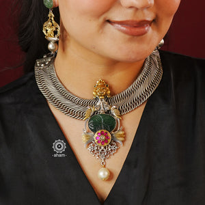 A beautiful contemporary dual tone neckpiece with the majestic Gir lion at the center, accompanied by craved green aventurine, beautiful peacock and lotus motifs, pink kundan highlight and finished off with a baroque pearl. Crafted in silver by karigars in India. 