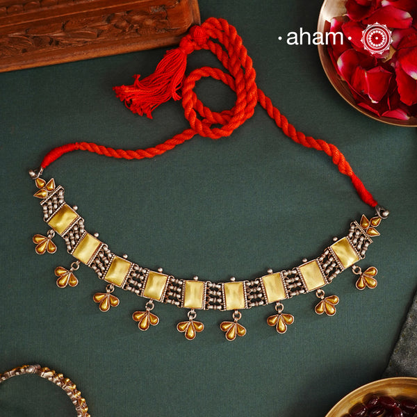 Enhance your style with the timeless elegance of the Two Tone Silver Choker. Handcrafted by skilled karigars in Barmer, Rajasthan, this neckpiece features traditional Bandhel work, where a thin sheet of hand beaten 22 carat gold is set on silver using a unique wax filling technique. A classic representation of Indian craftsmanship.