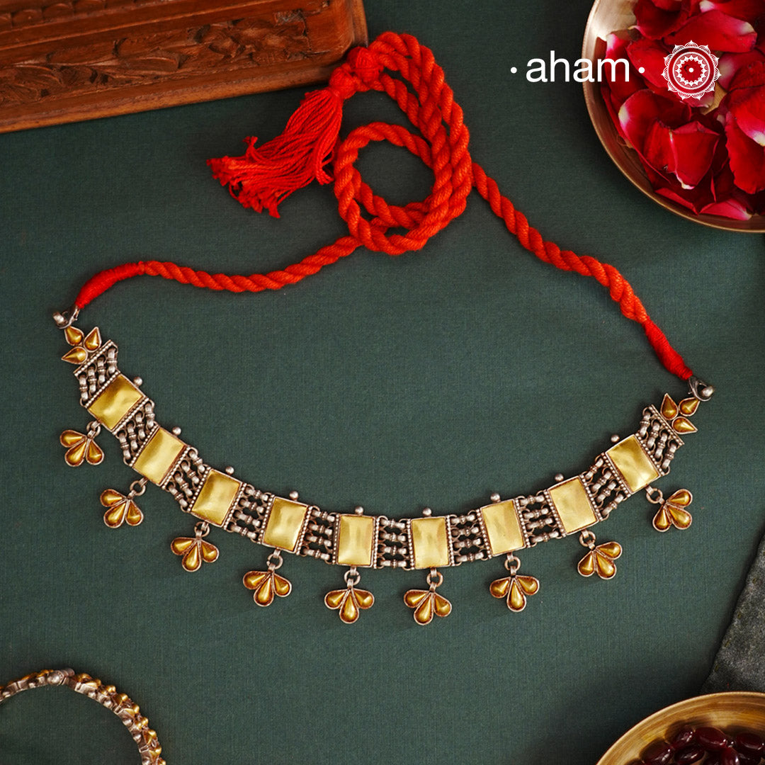 Enhance your style with the timeless elegance of the Two Tone Silver Choker. Handcrafted by skilled karigars in Barmer, Rajasthan, this neckpiece features traditional Bandhel work, where a thin sheet of hand beaten 22 carat gold is set on silver using a unique wax filling technique. A classic representation of Indian craftsmanship.