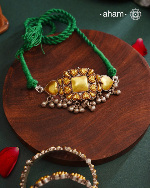 Enhance your style with the timeless elegance of the Dual Tone Silver Choker. Handcrafted by skilled karigars in Barmer, Rajasthan, this neckpiece features traditional Bandhel work, where a thin sheet of hand beaten 22 carat gold is set on 92.5 silver using a unique wax filling technique. A classic representation of Indian craftsmanship.