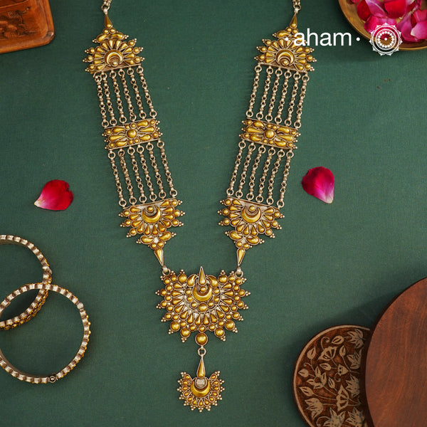 Enhance your style with the timeless elegance of the Dual Tone Silver Neckpiece. Handcrafted by skilled karigars in Barmer, Rajasthan, this earring features traditional Bandhel work, where a thin sheet of hand beaten 22 carat gold is fused with 92.5 silver and then set on 92.5 silver using a unique wax filling technique. A classic representation of Indian craftsmanship.