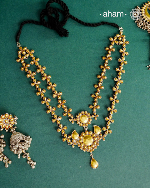 Enhance your style with the timeless elegance of the Dual Tone Silver Neckpiece. Handcrafted by skilled karigars in Barmer, Rajasthan, this earring features traditional Bandhel work, where a thin sheet of hand beaten 22 carat gold is fused with 92.5 silver and then set on 92.5 silver using a unique wax filling technique. A classic representation of Indian craftsmanship.