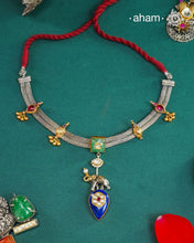 This Noori neckpiece showcases the artistry of traditional design in a contemporary dual-tone composition. Meticulously crafted in 92.5 sterling silver with warm gold highlights, this neckpiece features intricate motifs adorning the sides while a striking center drop combines deep blue lapis lazuli with an elephant charm—a symbol of grace and strength. The harmonious blend of heritage craftsmanship and gemstone elegance makes this piece a refined addition to both festive and everyday wear.