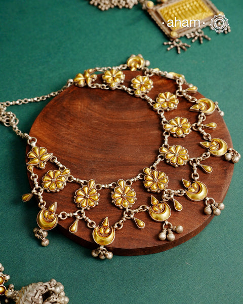 Enhance your style with the timeless elegance of the Dual Tone Silver Neckpiece. Handcrafted by skilled karigars in Barmer, Rajasthan, this earring features traditional Bandhel work, where a thin sheet of hand beaten 22 carat gold is fused with 92.5 silver and then set on 92.5 silver using a unique wax filling technique. A classic representation of Indian craftsmanship.