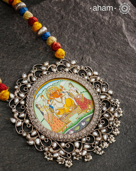 This hand-painted Ganesha neckpiece is a true piece of art. The miniature Ganesha is carefully painted by master artisans, set in silver with beautiful pearl work all around it and strung on a comfortable cotton thread. Add a touch of culture and beauty to your outfit with this unique silver neckpiece.