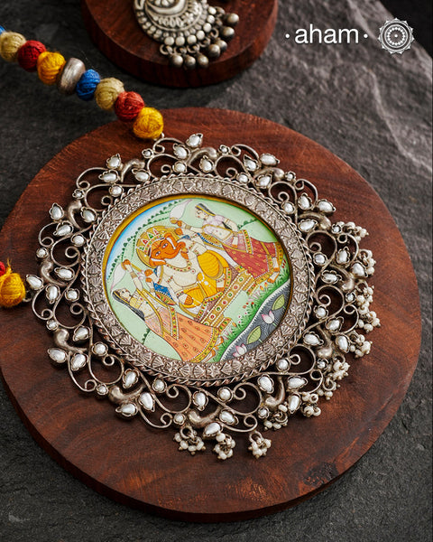 This hand-painted Ganesha neckpiece is a true piece of art. The miniature Ganesha is carefully painted by master artisans, set in silver with beautiful pearl work all around it and strung on a comfortable cotton thread. Add a touch of culture and beauty to your outfit with this unique silver neckpiece.