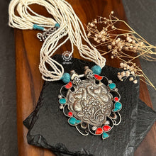 Crafted in 92.5 silver, the Ira Peacock Silver Neckpiece features a stunning peacock pendant adorned with turquoise and coral highlights. Elegant faux pearl strings complete this exquisite piece, making it perfect for any occasion. Elevate your style with this beautiful neckpiece.