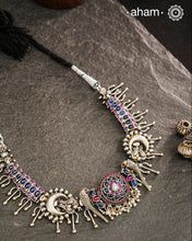 Meticulously crafted from 92.5 sterling silver, this exquisite Ira Parrot Silver Neckpiece features a central lotus pendant flanked by intricate parrot motifs. The design is enhanced with vibrant blue and maroon kemp stone accents, creating a striking contrast against the silver. Designed to rest elegantly below the neck, this piece combines traditional Indian artistry with sophisticated craftsmanship for a timeless addition to your jewelry collection.