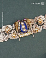 Discover the beauty of the Noori Two Tone Silver Choker. Simple yet unique, this wearable art piece is crafted in 92.5 silver with two tones and embellished with two parrots and lapiz at its center. With kundan and pearl highlights, this modern heirloom will be cherished for generations.
