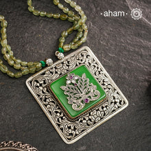 The Ira Silver Neckpiece features masterful chitai work with precise silver cutwork that sits on a luminous green center stone. The pendant is complemented by a strand of carefully selected semi-precious stone beads, enhancing its visual complexity. This exceptional piece demonstrates superior silversmithing techniques while offering a sophisticated aesthetic that transitions effortlessly from traditional to contemporary settings.