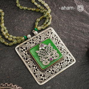 The Ira Silver Neckpiece features masterful chitai work with precise silver cutwork that sits on a luminous green center stone. The pendant is complemented by a strand of carefully selected semi-precious stone beads, enhancing its visual complexity. This exceptional piece demonstrates superior silversmithing techniques while offering a sophisticated aesthetic that transitions effortlessly from traditional to contemporary settings.