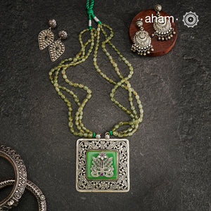 The Ira Silver Neckpiece features masterful chitai work with precise silver cutwork that sits on a luminous green center stone. The pendant is complemented by a strand of carefully selected semi-precious stone beads, enhancing its visual complexity. This exceptional piece demonstrates superior silversmithing techniques while offering a sophisticated aesthetic that transitions effortlessly from traditional to contemporary settings.