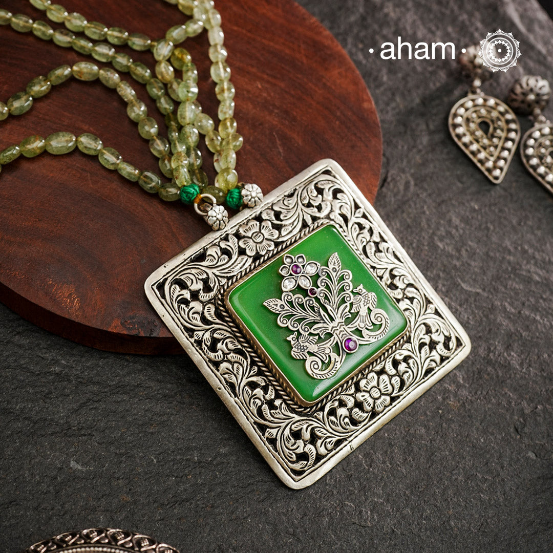 The Ira Silver Neckpiece features masterful chitai work with precise silver cutwork that sits on a luminous green center stone. The pendant is complemented by a strand of carefully selected semi-precious stone beads, enhancing its visual complexity. This exceptional piece demonstrates superior silversmithing techniques while offering a sophisticated aesthetic that transitions effortlessly from traditional to contemporary settings.