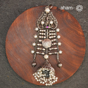 This unique Ganesha Pendant is a statement piece crafted in 92.5 silver. The intricate design features Ganesha at the top, flanked by delicately crafted peacocks on either side. A jhumka hangs at the bottom, adorned with pearl highlights for a touch of elegance. Elevate any outfit with this one-of-a-kind pendant.