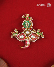An intricately crafted statement pendant inspired by traditional artistry and symbolism. Featuring delicate peacock motifs on either side and tiger nail motif at the bottom, this striking design is adorned with vibrant deep pink and green kundan work, highlighted with luminous stone settings and intricate pearl detailing. At the centre sits a beautifully carved green stone, adding depth and character to the composition. Crafted in 92.5 silver with a rich gold polish finish, this pendant is designed to stand