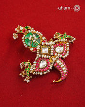 An intricately crafted statement pendant inspired by traditional artistry and symbolism. Featuring delicate peacock motifs on either side and tiger nail motif at the bottom, this striking design is adorned with vibrant deep pink and green kundan work, highlighted with luminous stone settings and intricate pearl detailing. At the centre sits a beautifully carved green stone, adding depth and character to the composition. Crafted in 92.5 silver with a rich gold polish finish, this pendant is designed to stand