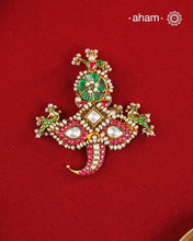 An intricately crafted statement pendant inspired by traditional artistry and symbolism. Featuring delicate peacock motifs on either side and tiger nail motif at the bottom, this striking design is adorned with vibrant deep pink and green kundan work, highlighted with luminous stone settings and intricate pearl detailing. At the centre sits a beautifully carved green stone, adding depth and character to the composition. Crafted in 92.5 silver with a rich gold polish finish, this pendant is designed to stand