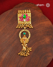 A striking pendant inspired by traditional symbolism and intricate craftsmanship. Featuring a beautifully detailed Ganesha motif suspended below a lotus adorned with deep pink and green kundan work, this piece celebrates artistry in every detail. Crafted in 92.5 silver with a rich gold polish finish, delicate ghungroo accents add movement and charm, making it a distinctive statement for festive and occasion wear..