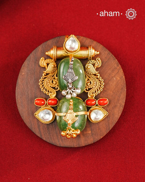 A harmonious composition of heritage-inspired elements, this statement pendant brings together tumble emeralds, coral accents, kundan highlights, and intricately detailed motifs in a beautifully layered form. The sculptural design, enhanced with delicate silver detailing and a rich gold polish finish, evokes the charm of vintage jewellery while feeling strikingly distinctive. Crafted in 92.5 silver, this pendant is perfect for adding an artistic, conversation-worthy touch to festive and occasion wear.