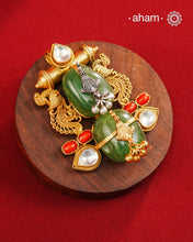 A harmonious composition of heritage-inspired elements, this statement pendant brings together tumble emeralds, coral accents, kundan highlights, and intricately detailed motifs in a beautifully layered form. The sculptural design, enhanced with delicate silver detailing and a rich gold polish finish, evokes the charm of vintage jewellery while feeling strikingly distinctive. Crafted in 92.5 silver, this pendant is perfect for adding an artistic, conversation-worthy touch to festive and occasion wear.