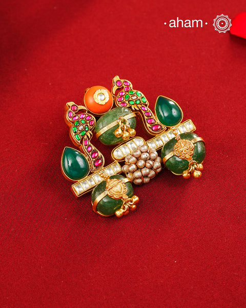 A vibrant celebration of traditional Indian artistry, this one of a kind handcrafted pendant is crafted in 92.5 sterling silver and finished with a rich gold polish. The design features a pair of intricately detailed peacocks adorned with ruby and emerald-toned stones, symbolising beauty, grace, and prosperity. At the centre, emerald quartz beads, kundan accents, and delicate ghungroo clusters come together to create a striking composition rich in colour and craftsmanship.