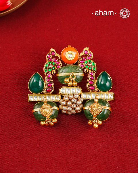 A vibrant celebration of traditional Indian artistry, this one of a kind handcrafted pendant is crafted in 92.5 sterling silver and finished with a rich gold polish. The design features a pair of intricately detailed peacocks adorned with ruby and emerald-toned stones, symbolising beauty, grace, and prosperity. At the centre, emerald quartz beads, kundan accents, and delicate ghungroo clusters come together to create a striking composition rich in colour and craftsmanship.