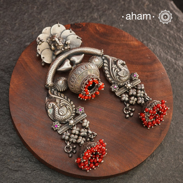 Crafted in 92.5 silver, this large statement Ganesha pendant is truly one of a kind. Featuring beautiful peacocks and coral highlights, it's a unique piece that will make a bold and elegant addition to any outfit. Elevate your style with this exquisite silver pendant.