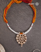 This finely crafted tribal silver amulet pendant, originating from Madhya Pradesh, reflects the heritage and stories of a bygone era. It is accompanied by a striking thread powai, enhancing its traditional appeal.