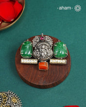 This exquisite Two Tone Silver Pendant showcases stunning krishna nakshi work accented with a vibrant emerald tumble stone and kundan highlights. Handcrafted in 92.5 silver, it is truly one of a kind. Elevate any outfit with its unique and beautiful design.