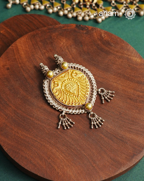 Enhance your style with the timeless elegance of the Dual Tone Silver Pendant. Handcrafted by skilled karigars in Barmer, Rajasthan, this neckpiece features traditional Bandhel work, where a thin sheet of hand beaten 22 carat gold is set on 92.5 silver using a unique wax setting technique. A classic representation of fine Indian traditional craftsmanship.