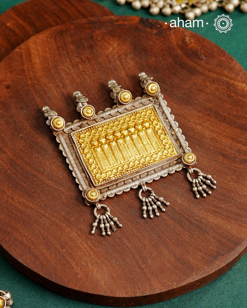 Enhance your style with the timeless elegance of the Dual Tone Silver Pendant. Handcrafted by skilled karigars in Barmer, Rajasthan, this neckpiece features traditional Bandhel work, where a thin sheet of hand beaten 22 carat gold is set on 92.5 silver using a unique wax setting technique. A classic representation of fine Indian traditional craftsmanship.