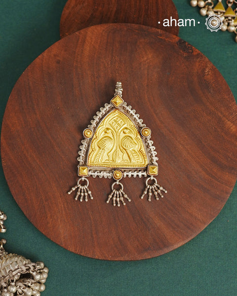 Enhance your style with the timeless elegance of the Dual Tone Silver Pendant. Handcrafted by skilled karigars in Barmer, Rajasthan, this neckpiece features traditional Bandhel work, where a thin sheet of hand beaten 22 carat gold is set on 92.5 silver using a unique wax setting technique. A classic representation of fine Indian traditional craftsmanship. 

Chain not included