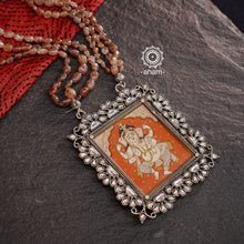 This Ganesha Hand Painted Silver Neckpiece is a true masterpiece, featuring a hand-painted Ganesha set in intricately crafted silver and adorned with stunning Kundan work and beautiful semi precious stone strings. Add an elegant touch of the divine to any outfit with this unique and eye-catching neckpiece.