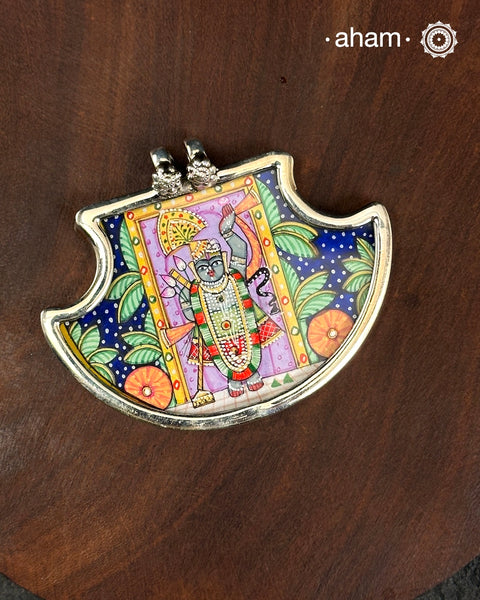 A tribute to devotion, heritage, and Indian artistry, this Pichwai Shrinathji Pendant is handcrafted in 92.5 sterling silver and features a beautifully hand-painted depiction of Shrinathji, inspired by the iconic Pichwai paintings of Nathdwara, Rajasthan.

Framed in sterling silver, the miniature artwork captures the divine presence of Shrinathji amidst traditional Pichwai elements, transforming a timeless art form into a wearable keepsake. Every pendant is individually hand-painted by skilled artisans,