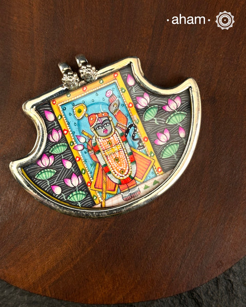 A tribute to devotion, heritage, and Indian artistry, this Pichwai Shrinathji Pendant is handcrafted in 92.5 sterling silver and features a beautifully hand-painted depiction of Shrinathji, inspired by the iconic Pichwai paintings of Nathdwara, Rajasthan.

Framed in sterling silver, the miniature artwork captures the divine presence of Shrinathji amidst traditional Pichwai elements, transforming a timeless art form into a wearable keepsake. Every pendant is individually hand-painted by skilled artisans, 