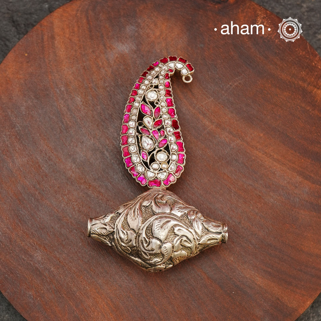 Enhance your style with the unique Ira Morpankh Silver Pendant. Featuring a stunning ambi kalki and chitai bead, this one-of-a-kind pendant can be worn with a chain or hasli, adding elegance to any outfit. Upgrade your look with this exquisite piece.(Does not include chain)