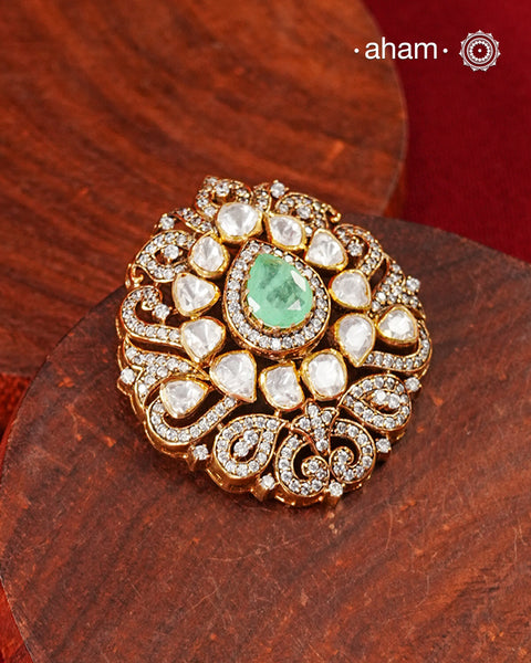 A celebration of classic craftsmanship, this pendant features a striking green center stone framed by shimmering moissanites in an intricate floral design.Crafted in 92.5 silver and finished in gold polish, it is a versatile piece that effortlessly elevates festive, wedding, and occasion wear.