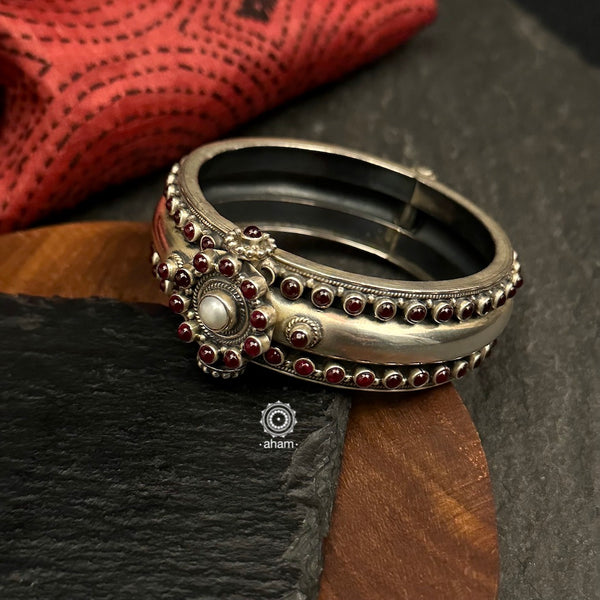 This handcrafted silver Kada is adorned with a stunning maroon Kemp Stones and pearl highlight. The openable design is made in 92.5 silver. Add a touch of traditional sophistication to any outfit with this Kemp Work Silver Kada.