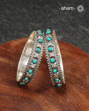 Handcrafted 92.5 sterling silver bangles with floral work interspersed with turquoise highlights. Comes as a pair.