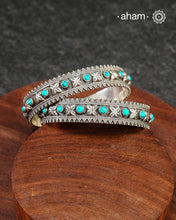 Handcrafted 92.5 sterling silver bangles with floral work interspersed with turquoise highlights. Comes as a pair.