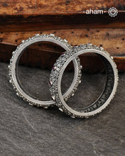 These handcrafted bangles showcases the exceptional skill of Kolhapur's master karigars, created entirely from 92.5 sterling silver with striking kemp stone accents.The bangle demonstrates superior craftsmanship through its precise construction and refined finish. Kemp highlights add textural depth and visual interest to the classic kada silhouette. An investment piece that honours traditional jewellery-making heritage while offering versatile styling for both formal occasions and daily adornment
